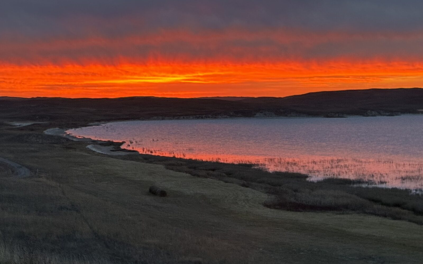 Fiery sunrise over Lake Alkali with hay bale